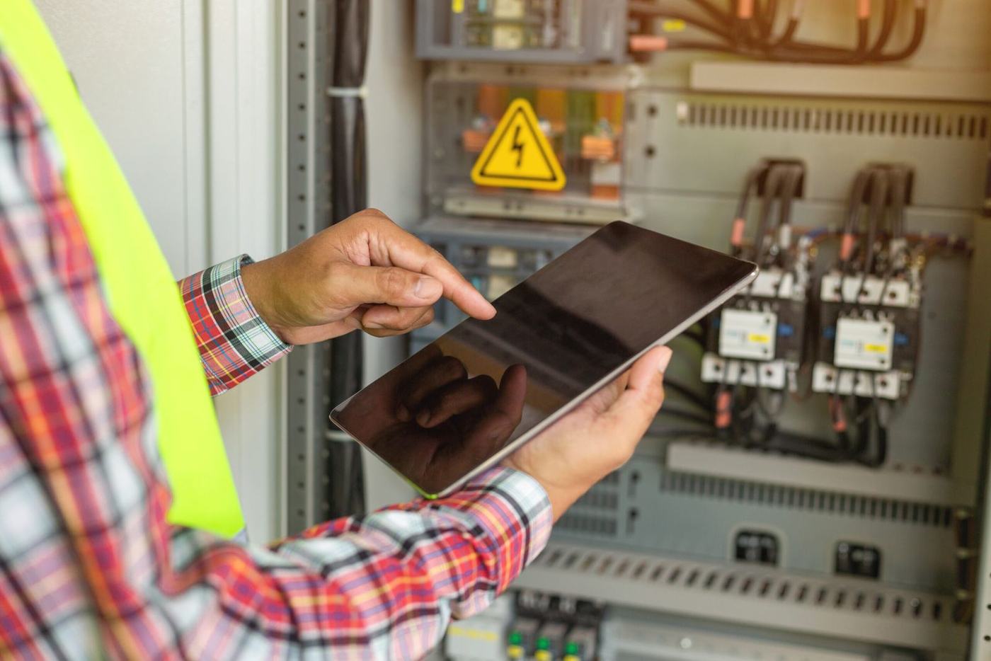 Elektriker prüft einen Schaltschrank mit dem Tablet