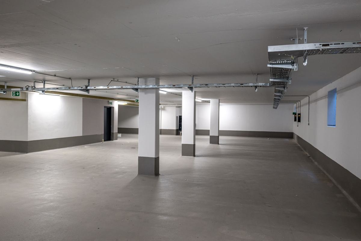 Beleuchtete Tiefgarage mit Kabeltrassen